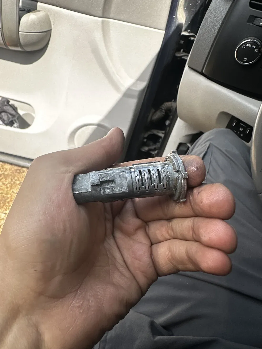 An ignition lock cylinder removed from a vehicle and resting in an open palm