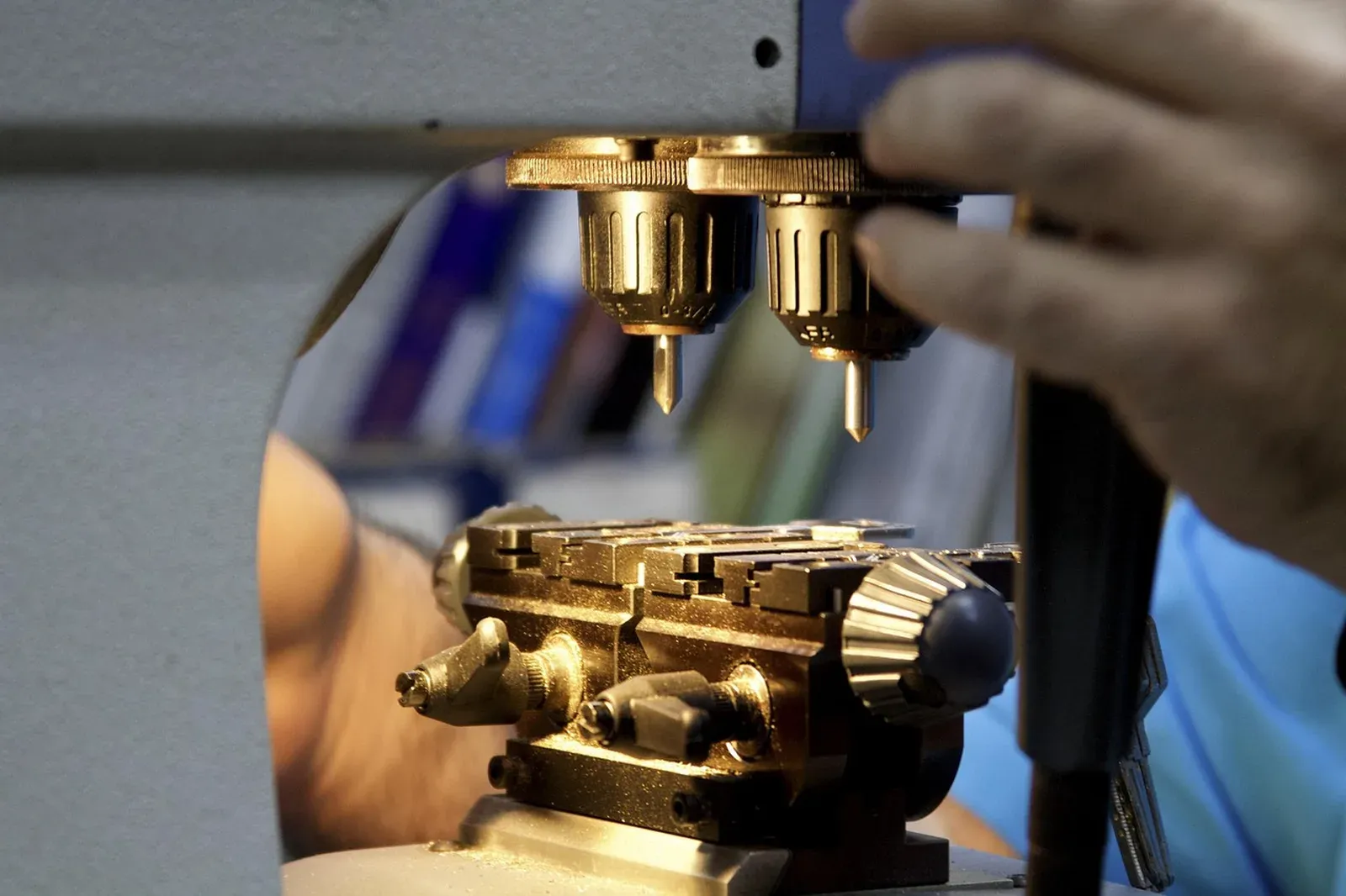 Close view of a brass key cutting machine with a hand operating the clamp and cutters