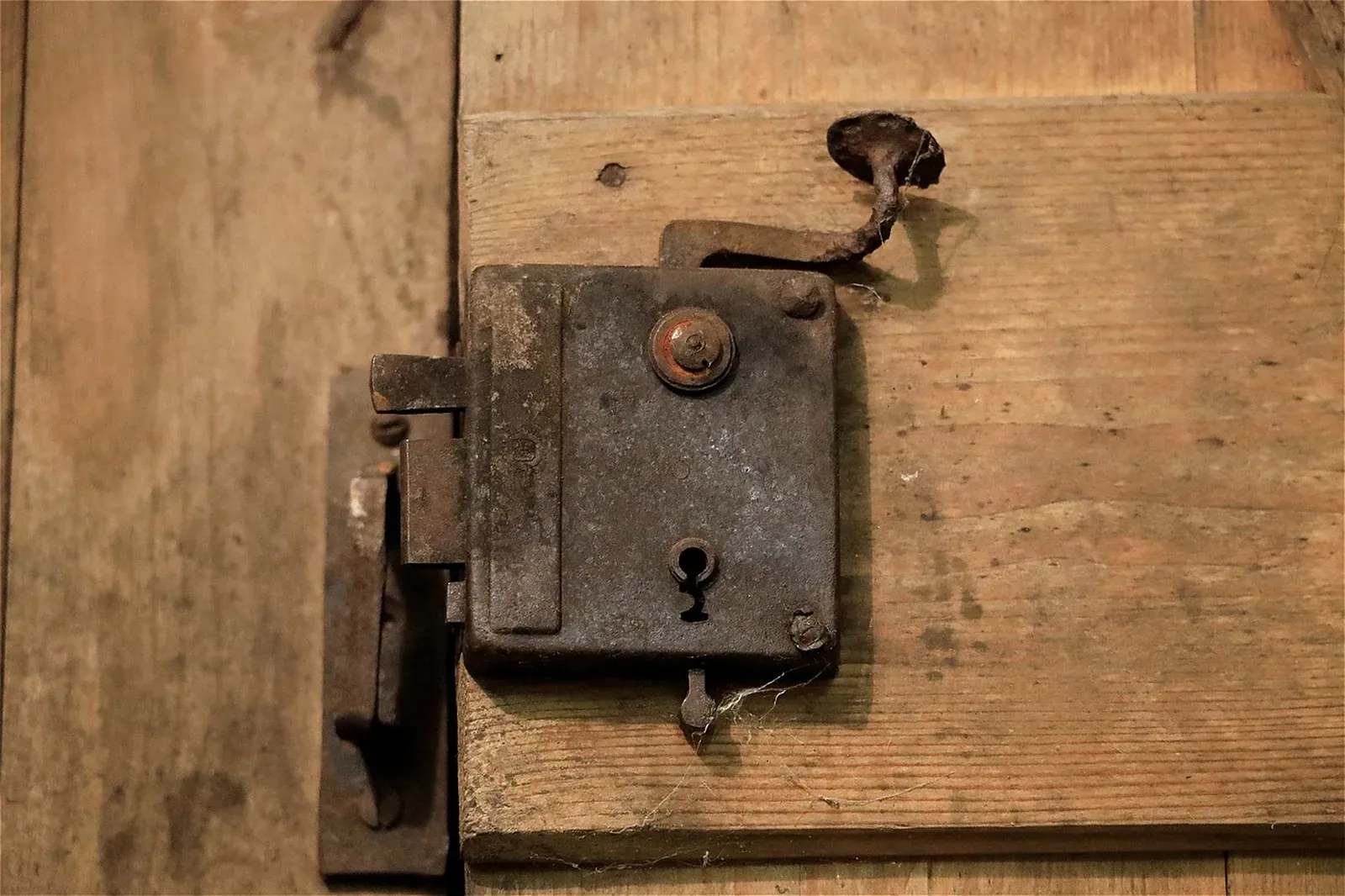 Aged iron mortise lock with keyhole and latch bolt mounted on a plank wooden door